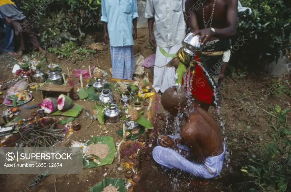 Sri Lanka, Haputale, Funeral Ritual With Son Of The Deceased With Head Shaved As Sign Of Bereavement Having Water Poured Over Him While Sitting On Ground Beside Fire And Offerings.