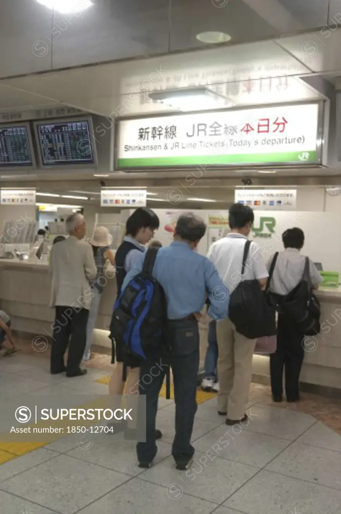 Japan, Tokyo , Tokyo Station With Customers Waiting To Buy Shinkansen Aka Bullet Train Tickets At A Desk With Bilingual Signs Above
