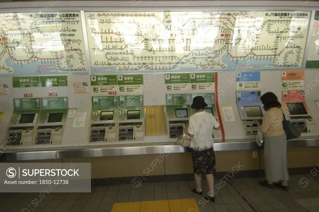 Japan, Honshu, Tokyo, Ueno Train Station With Women Buying Train Tickets From Vending Machines With The Train Route Map Above