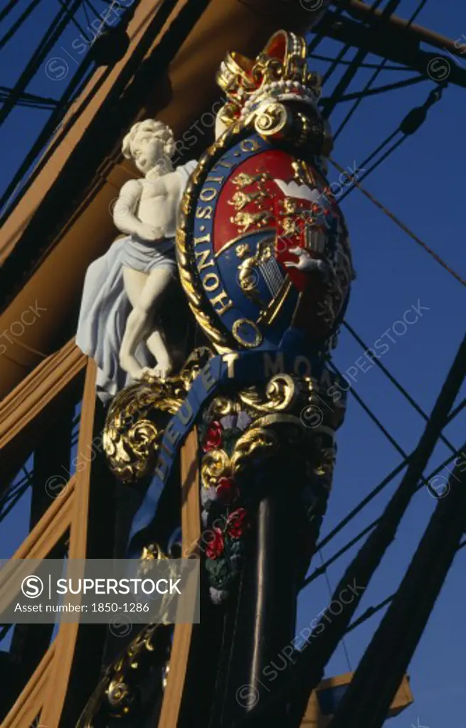 England, Hampshire, Portsmouth, Admiral Lord Nelson'S Hms Victory. Detail Of Elaborate Figurehead Of Two Cupids Supporting The Royal Coat Of Arms And Royal Crown. The Arms Bear The Norman French Inscription Of The Order Of The Garter Honi Soit Qui Mal Y Pense Which Means-Shame To Him Who Evil Thinks