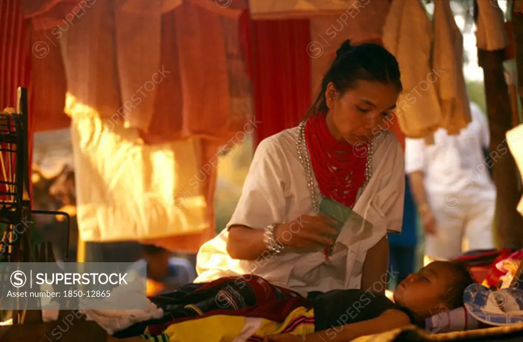 Thailand, Chiang Mai Province, Lawa Woman Inside Her House Fanning Her Young Sleeping Son
