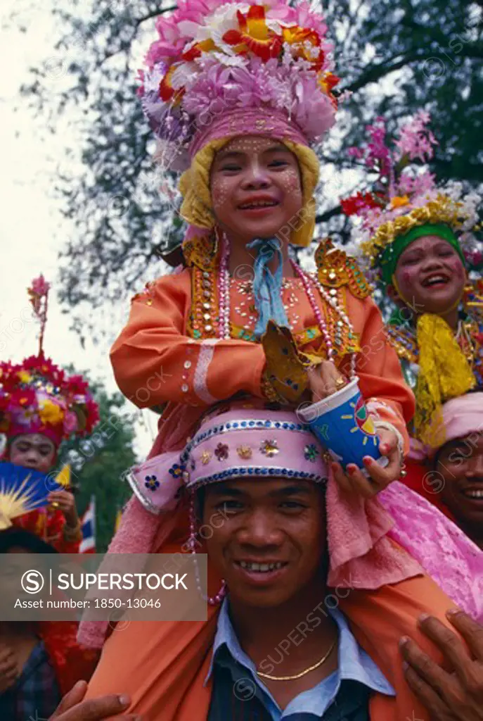Thailand, Chiang Mai, Shan Poi San Long. Crystal Children Ceremony With Luk Kaeo In Costume Sitting On Mans Shoulders At Wat Pa Pao