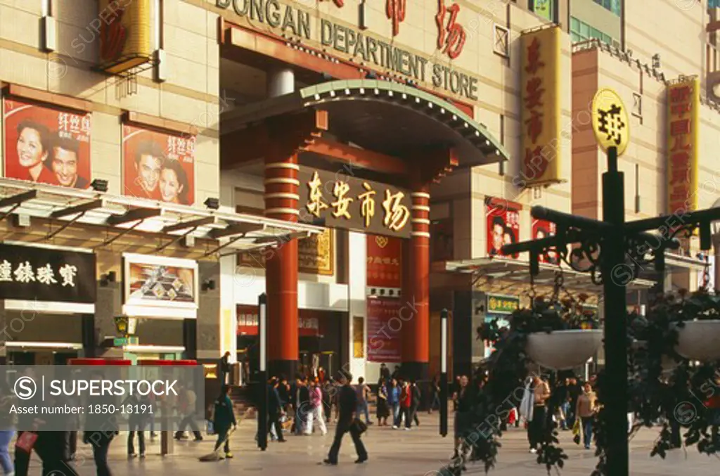China, Beijing, Wanfujing Dajie Department Store.  Entrance On To Busy Street With Advertising Covering Exterior Wall.