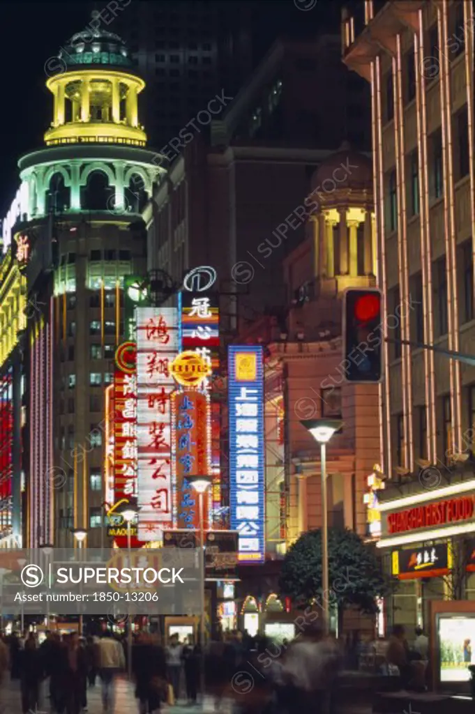 China, Shanghai, Nanjing Road At Night With Illuminated Neon Signs And Crowds Of People In Blurred Movement Below.