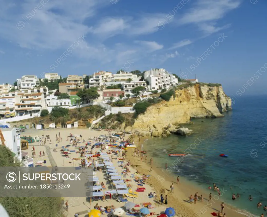 Portugal, Algarve, Carvoeiro, White Painted Town On Rocky Headland Overlooking Busy Beach.