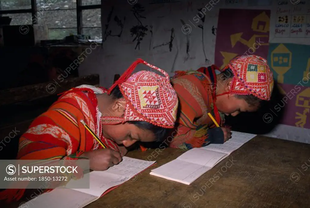 Peru, Andes, Cusco, 'Tastayoc Village.  Quechua Indian Children Wearing Traditional Clothing, In School Writing At Desk.'