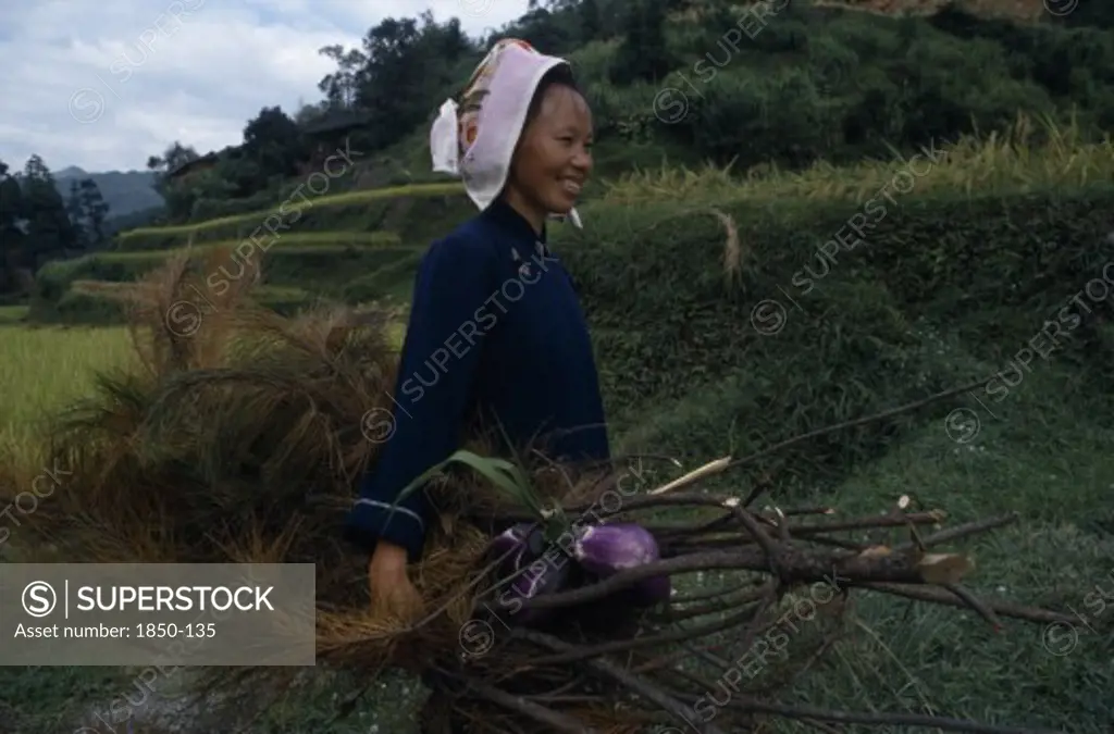 China, Guizhou, Leishan, Woman Carying Branches And Vegetation And Aubergines.