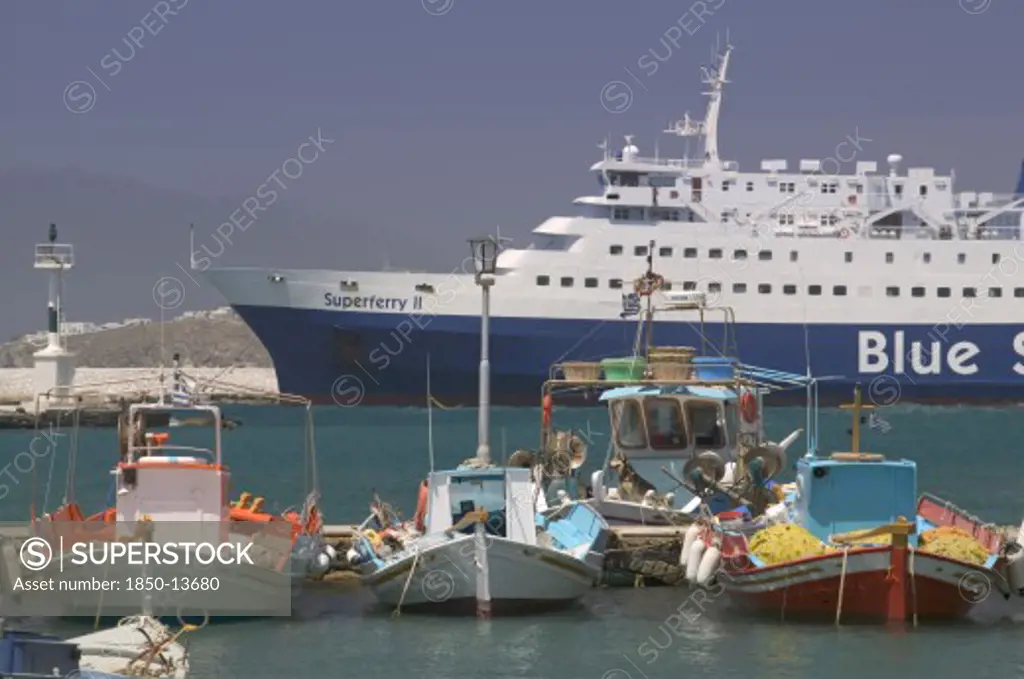 Greece, Cyclades, Mykonos, Passenger Ferry In Port With Colourful Fishing Boats In The Foreground.