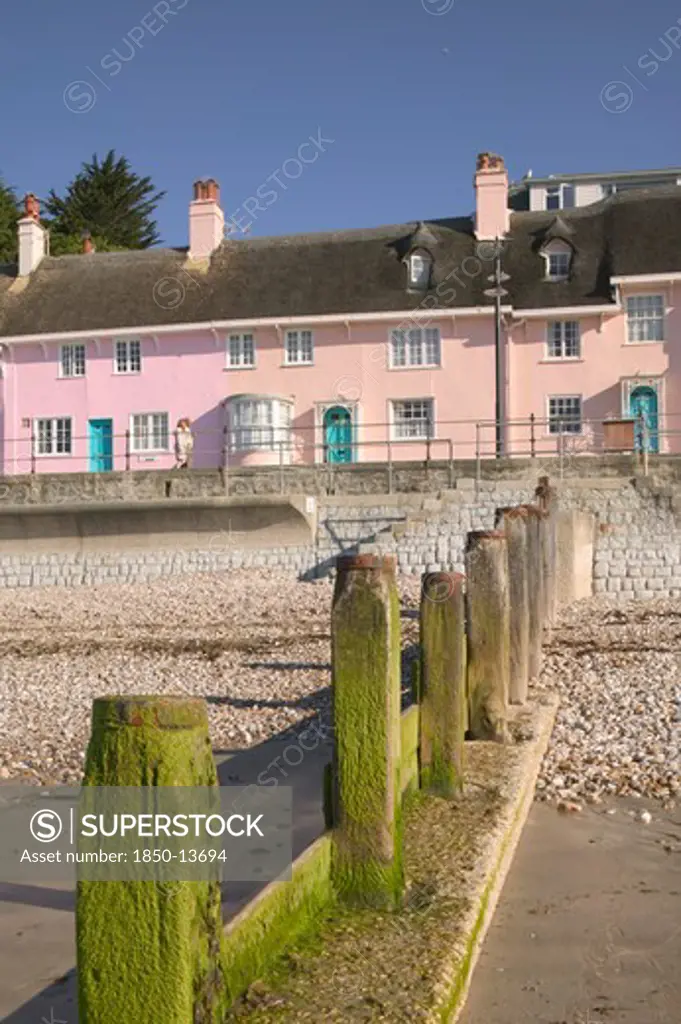 England, Dorset, Lyme Regis, View Of Old Fishermens Cottages Along The Waterfront From The Beach With A Groyne In The Foreground.