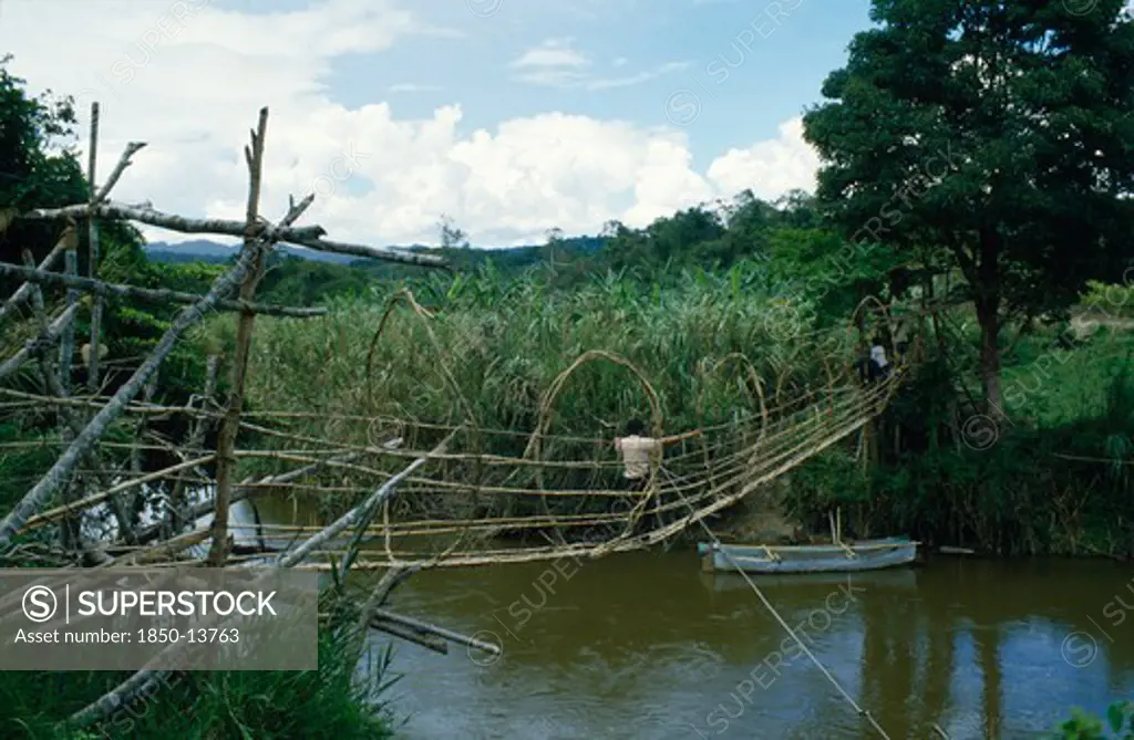 Indonesia, Sulawesi, Napu Valley. Bamboo Bridge Over River With People Crossing Over.