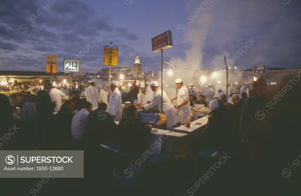 Morocco, Marrakesh, Djemaa El Fna. Food Vendors Serving Up Food To Hungry Customers Seated Around Them At Dusk