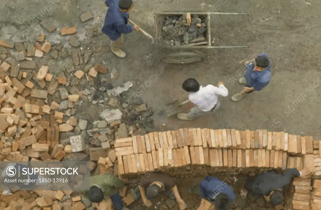 China, Sichuan, Chengdu, Construction Site.  Looking Down On Workers Stacking Bricks And Moving Rubble.