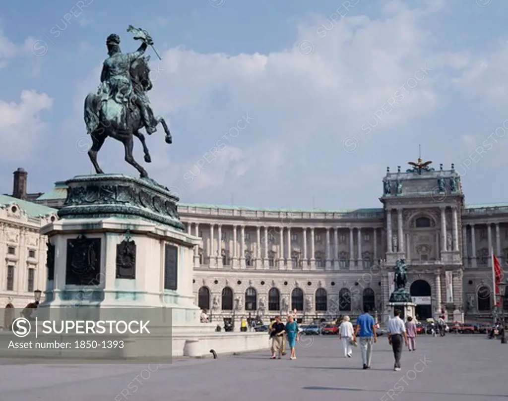 Austria, Lower Austria, Vienna, Hofburg Palace. Equestrian Statue On Plinth Standing In Courtyard Outside Semi Circular Facade With Passing People.