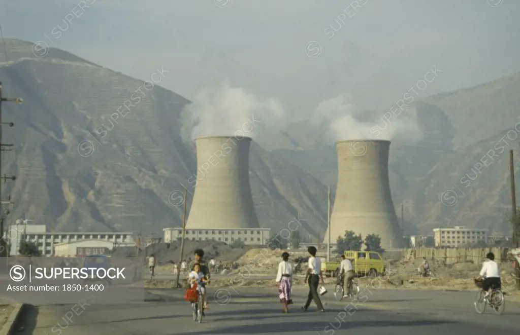 China, Gansu Province, Lanzhou, Coal Power Station With People Walking In The Foreground.