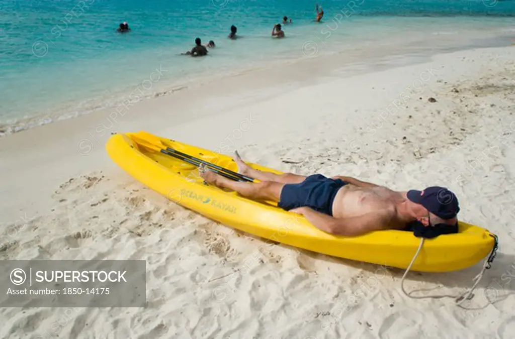 West Indies, St Vincent & The Grenadines, Tobago Cays, Man Lying In Kayak Sunbathing On The Beach Of Petit Bateau