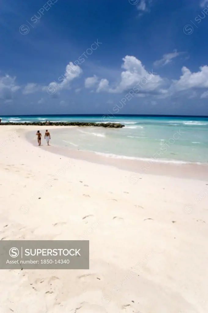 West Indies, Barbados, Christ Church, Couple Walking Towards Sea Defences On Rockley Beach Also Known As Accra Beach After The Hotel There