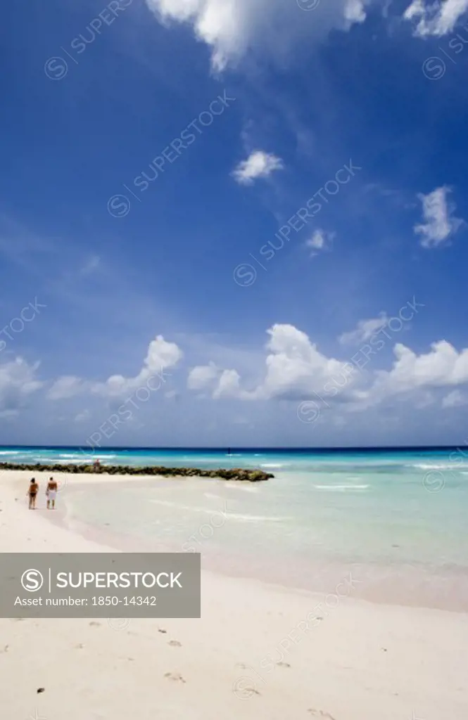 West Indies, Barbados, Christ Church, Couple Walking Towards Sea Defences On Rockley Beach Also Known As Accra Beach After The Hotel There