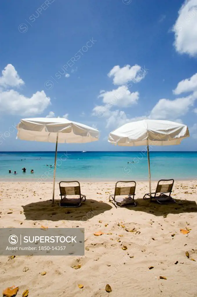 West Indies, Barbados, St Peter, Sun Shade Umbrellas And Chairs On Gibbes Beach With People Swimming In The Calm Sea