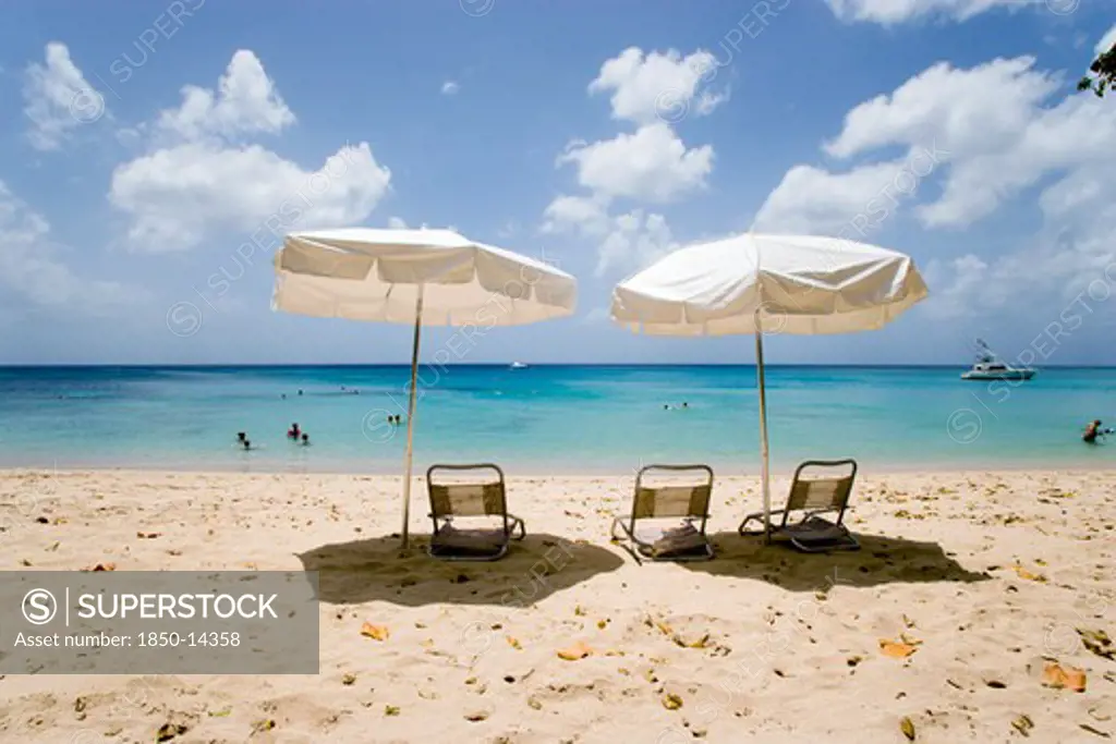 West Indies, Barbados, St Peter, Sun Shade Umbrellas And Chairs On Gibbes Beach With People Swimming In The Calm Sea