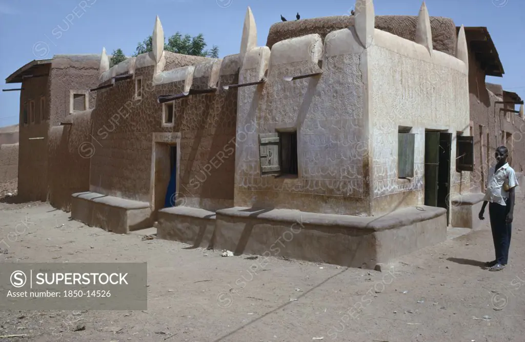 Nigeria, Kano, Traditional Hausa Dwelling And Mud Architecture With Man Standing Outside.