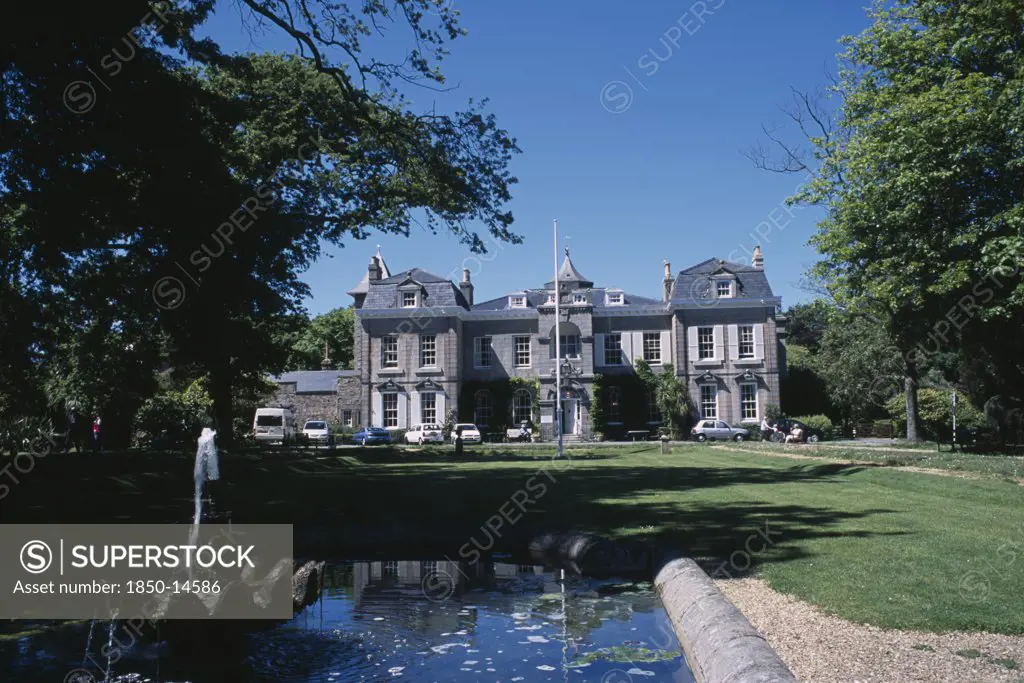 United Kingdom, Channel Islands, Guernsey, St Martins. Saumarez House. View Of Front Entrance From Green Lawn Over Pond.