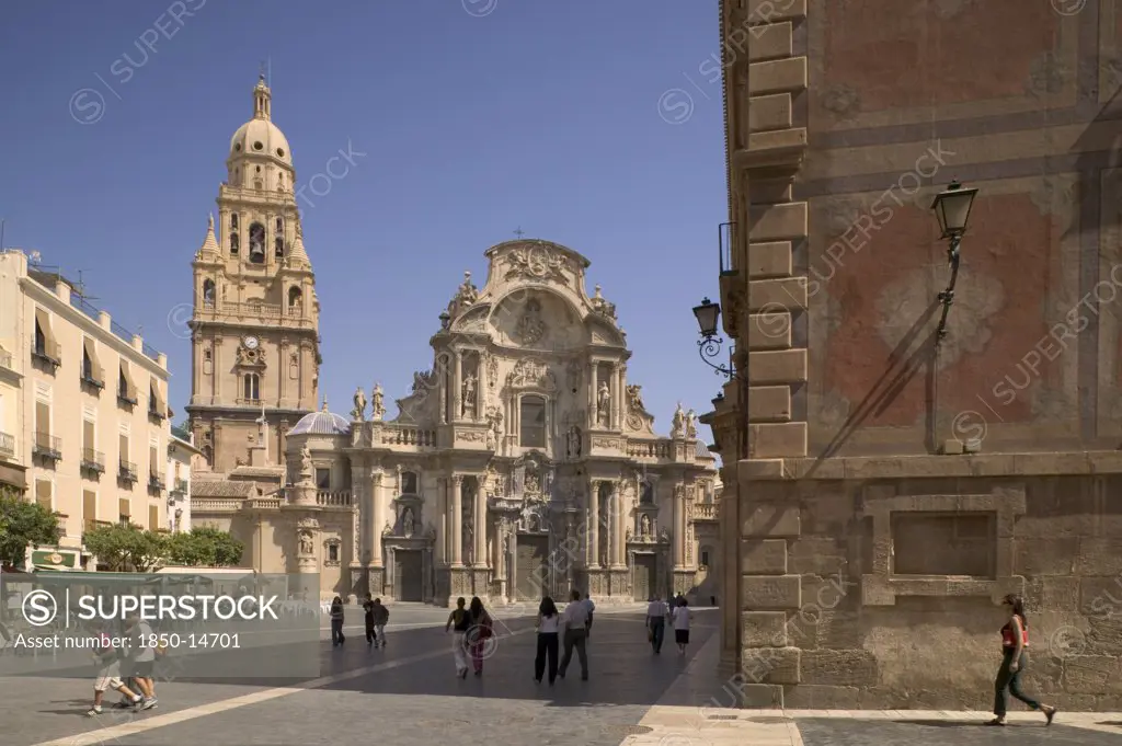 Spain, Murcia, Cathedral De Santa Maria And Plaza Del Cardenal Belluga With People Walking Past.