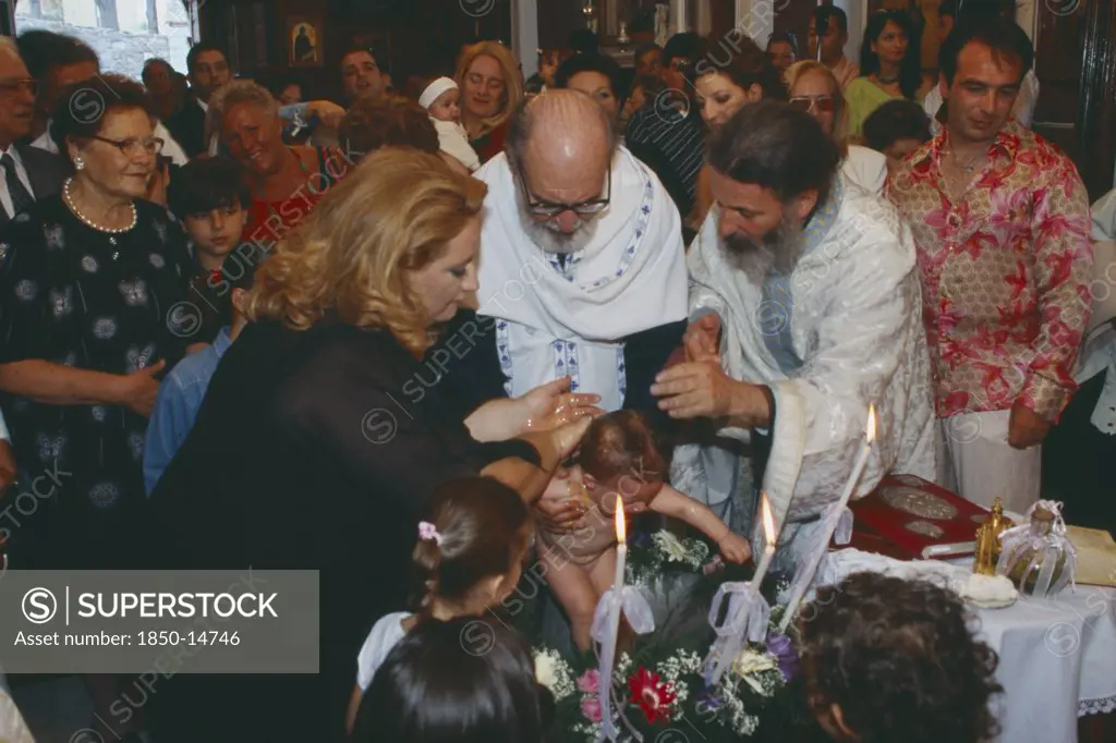 Greece, Cyclades Islands, Syros, 'A Greek Orthodox Christening, The Child Being Held And Water Poured Over Him With Friends And Family Watching From Behind.'