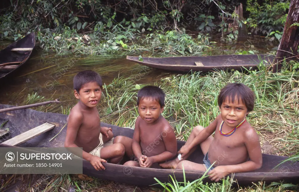 Colombia, Vaupes, Three Tukano Indian Boys Sat In Canoe And Empty Canoe Behind Them.