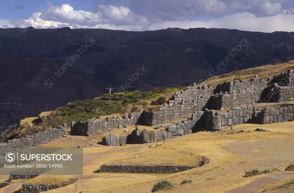 Peru, Cuzco, 'Sacsayhuaman Inca Site, People Walking Round The Old Walls And A Cross In The Background.'
