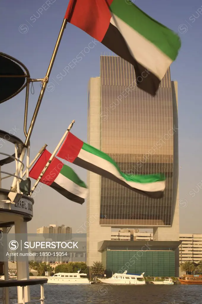 Uae, Dubai, The National Bank With Emirates National Flags Flying From The Stern Of A Boat In The Foreground.