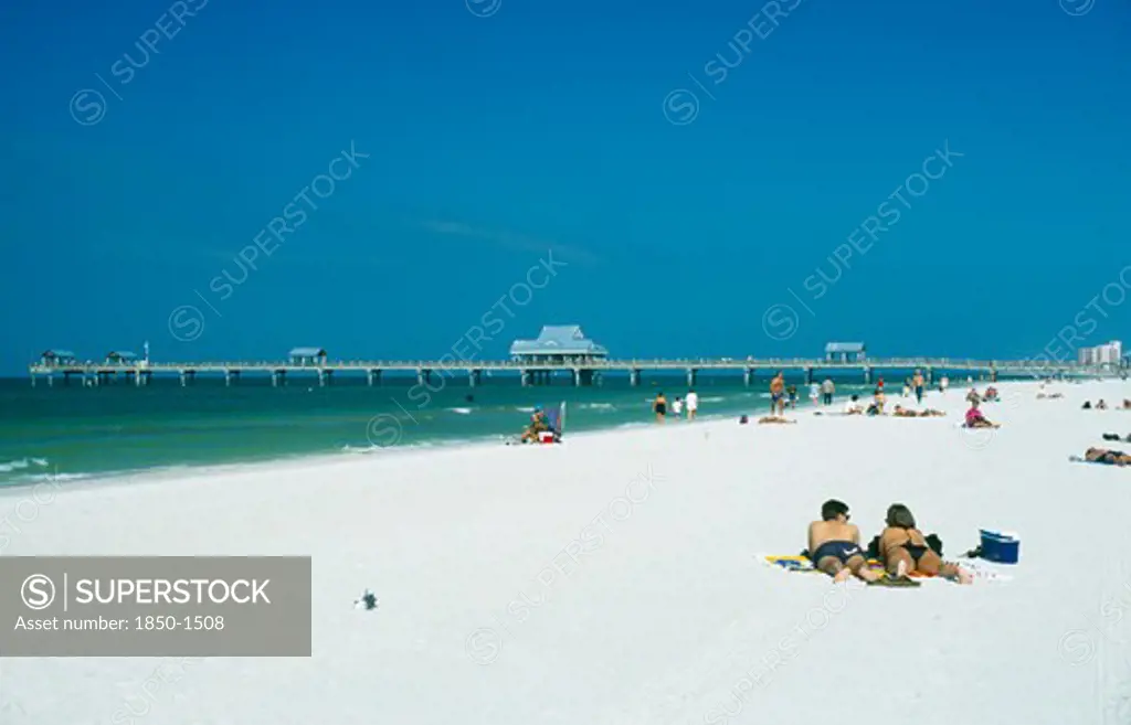 Usa, Florida , Clearwater Beach, Sunbathers On White Sand Beach With Pier Beyond.