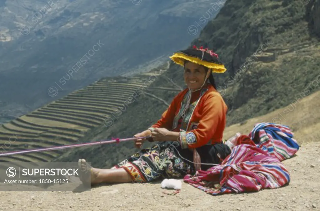 Peru, Cusco, Pisac, 'Quechuan Indian Woman Weaving, Inca Terracing Behind. Sacred Valley'