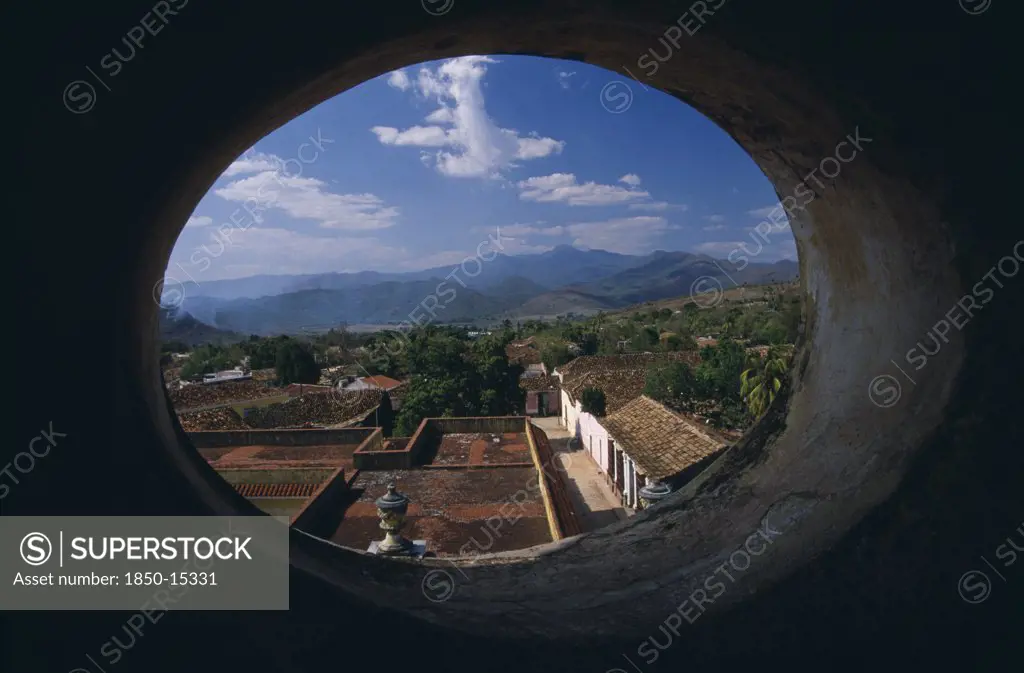 Cuba, Trinidad, View Across Red Tiled City Rooftops Framed By Oval Window In Iglesia San Franciso De Paula.