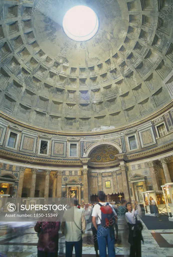 Italy, Lazio, Rome, 'Pantheon.  Interior Of Roman Temple, Visitors Looking Up At Circular Opening Or Oculus In Domed Ceiling Leeing In Beam Of Light.'