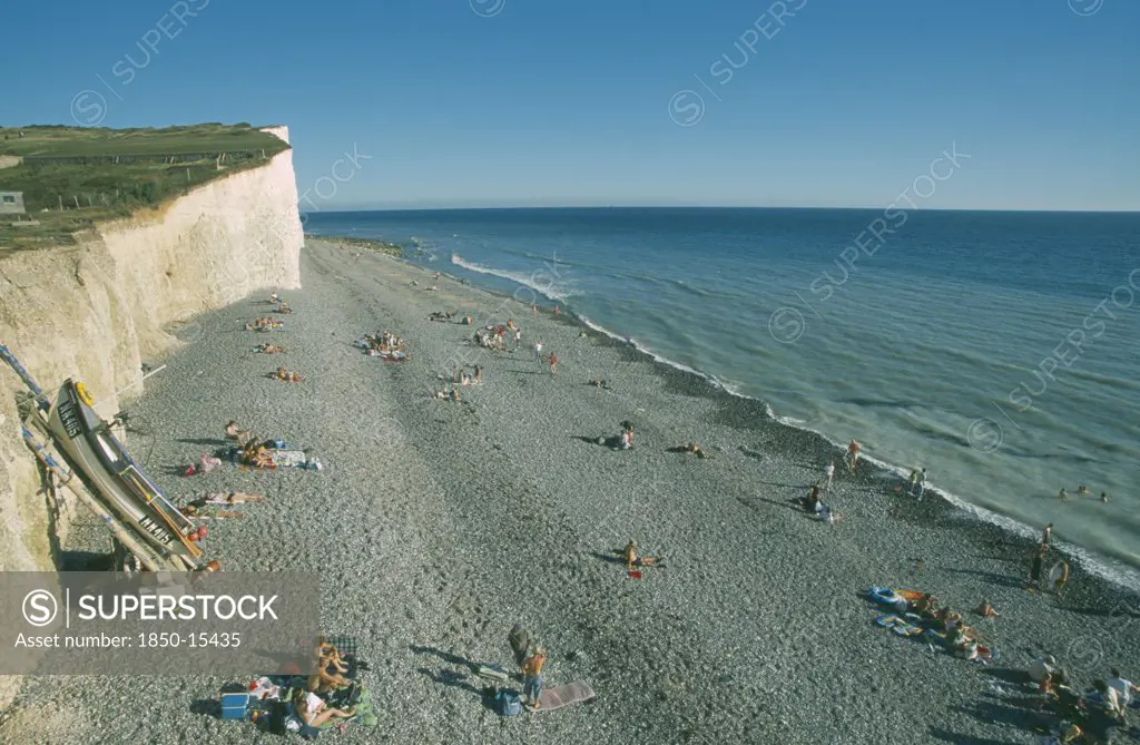 England, East Sussex, Birling Gap, View Over Occupied Peeble Beach With Boat Leaning Against Cliff Face.