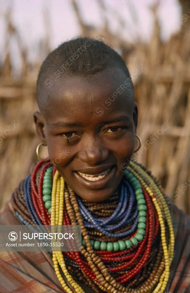 Uganda, Karamoja District, Portrait Of Karamojong Woman Wearing Multiple Coloured Bead Necklaces.  Her Hair Style Indicates Her Clan.