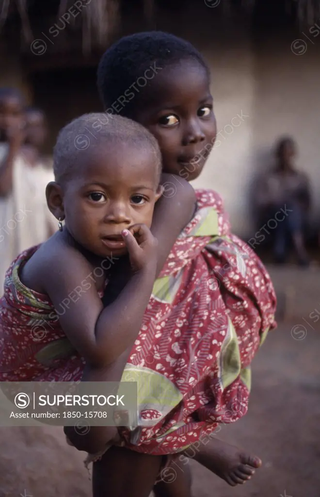 Ghana, Volta Region, Hohoe, Young Girl Looking After Little Sister Carried On Her Back.