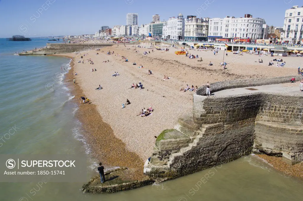 England, East Sussex, Brighton, The Beach And Seafront With Flint Groyne In The Foreground Seen From Brighton Pier With The City In The Distance