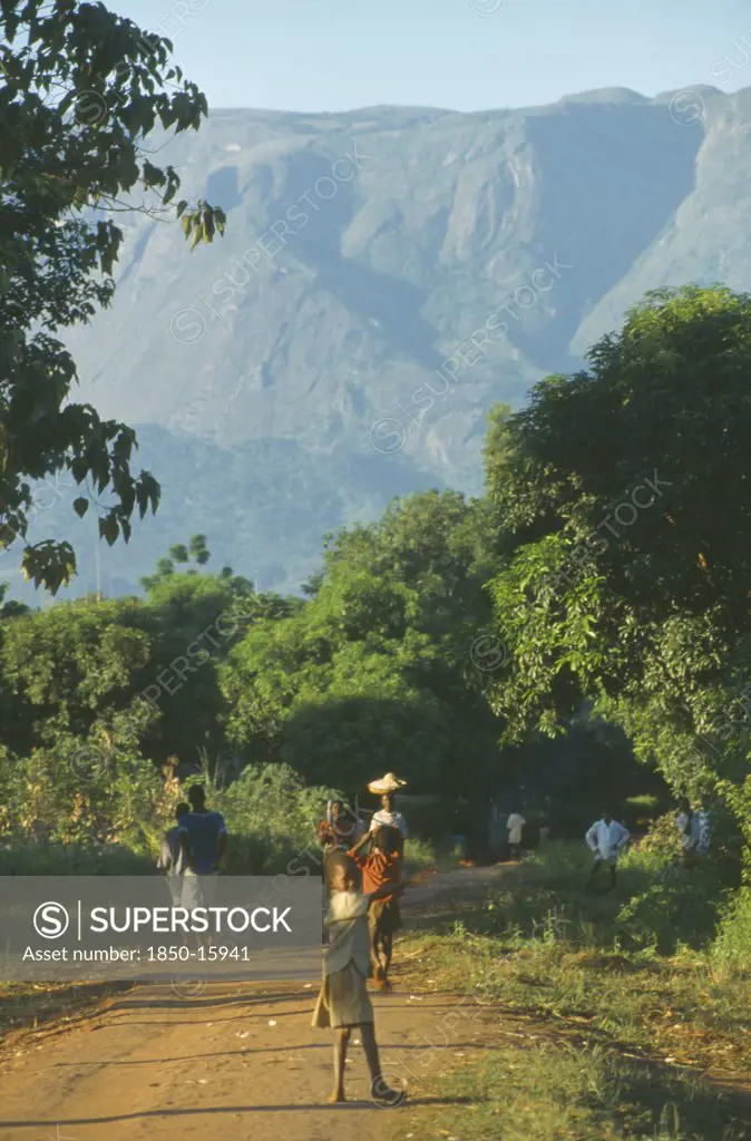 Malawi, Mulanje, People Walking Along Path In Area Of Tea Growing And Subsistence Farming With Mount Mulanje In The Distance.