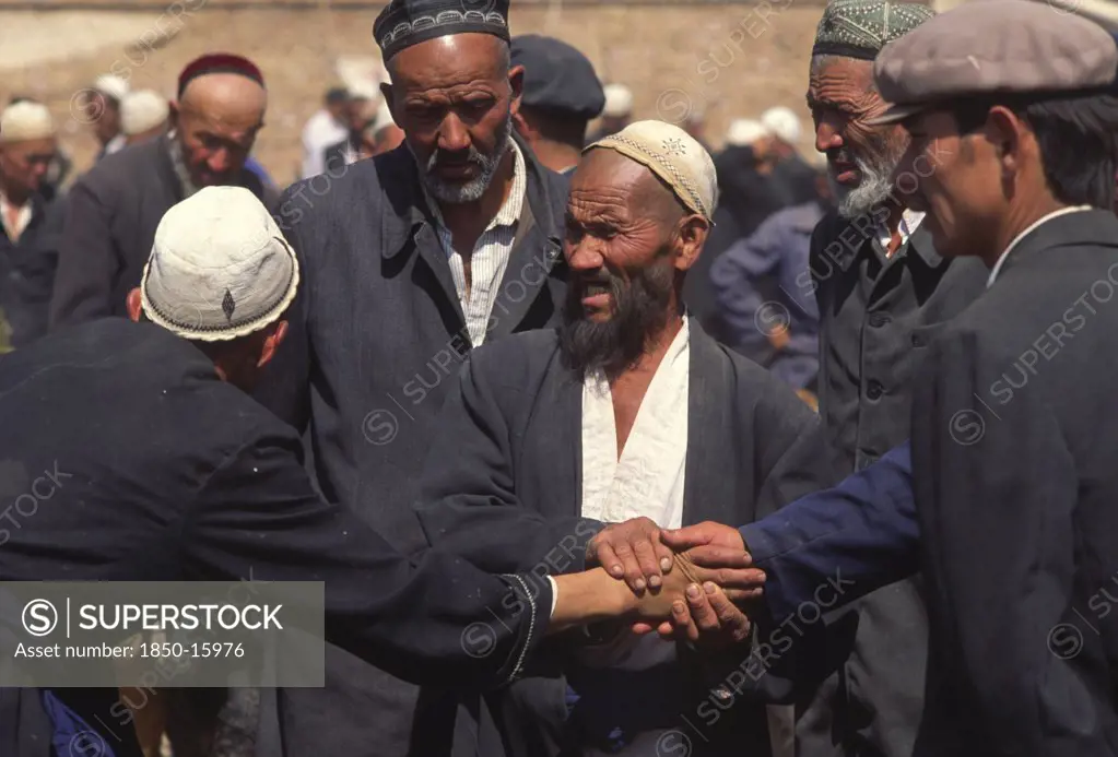 China, Xinjiang Province, Kashgar, Tajik Men Touching Hands Striking A Deal With Central Man Acting As A Witness