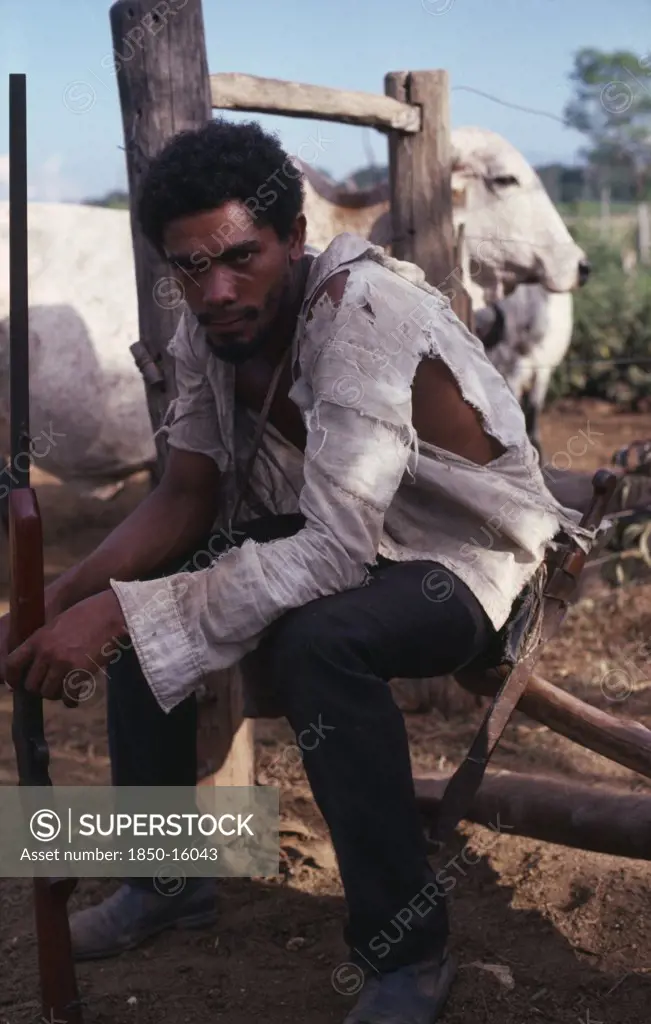 Brazil, State Of Para, 'Bela Vista Ranch. Portrait Of A Squatter Armed With A Shotgun, Sat Down With Torn Clothing.'