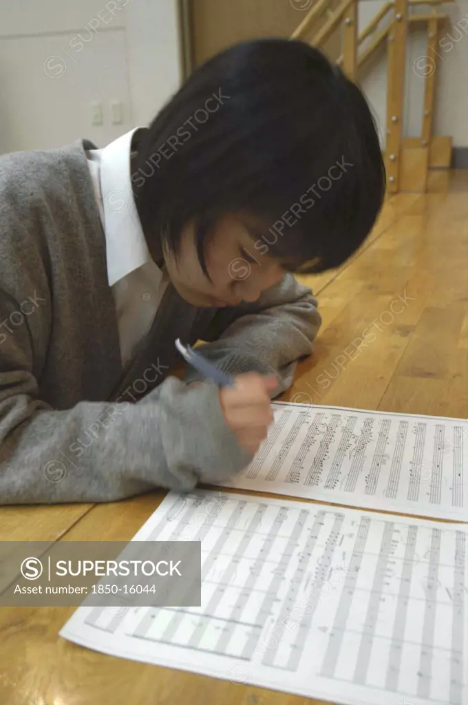 Japan, Chiba, Yokaichiba, Teenage Girl Writing Notes On Her Sheet Music. Plays Violin In United Freedom Orchestra