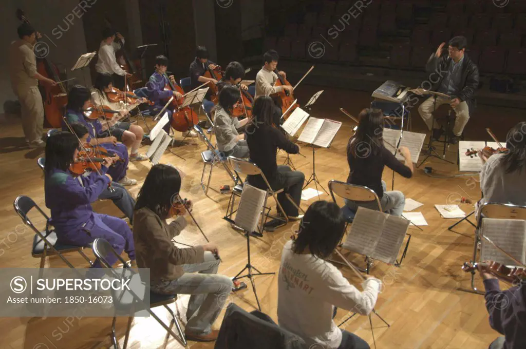 Japan, Chiba, Yokaichiba, Conductor And Music Teacher Leading Junior And Senior High School Students In Dress Rehearsal For Spring Concert In The United Freedom Orchestra