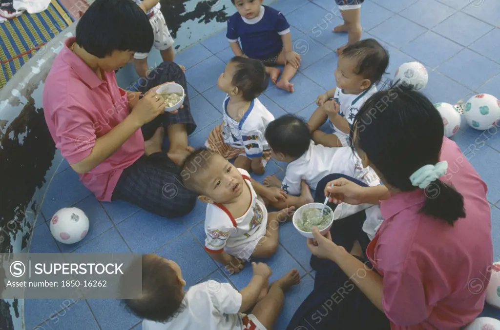 Thailand, North, Chiang Mai, Staff Feeding Young Children In Vienping Orphanage.