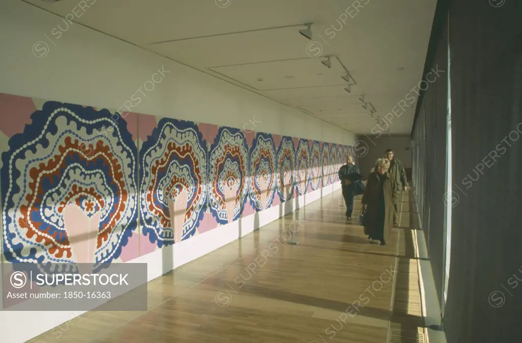 England, East Sussex, Bexhill On Sea, De La Warr Pavilion. Interior View Of Exhibition Space With A Colourful Art Display On Walls And Visitors Walking Through.