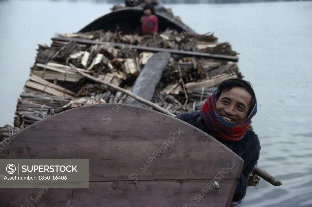 Vietnam, Central, Hue, Smiling Boatman On Barge Laden With Timber.
