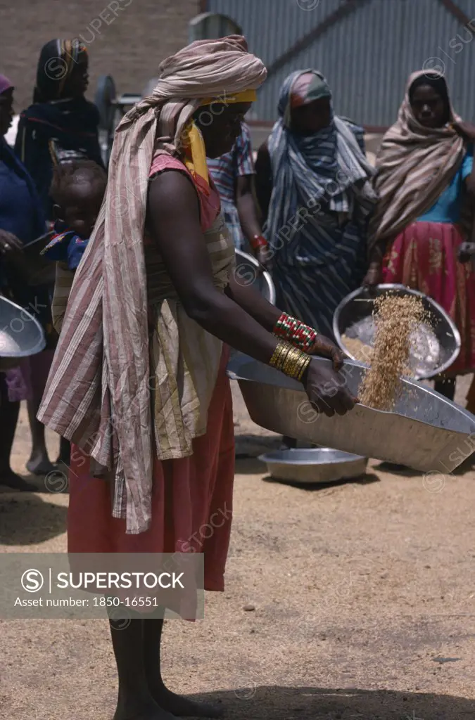 Sudan, Work, Nigerian Woman With Child In Sling On Her Back Winnowing Grain.