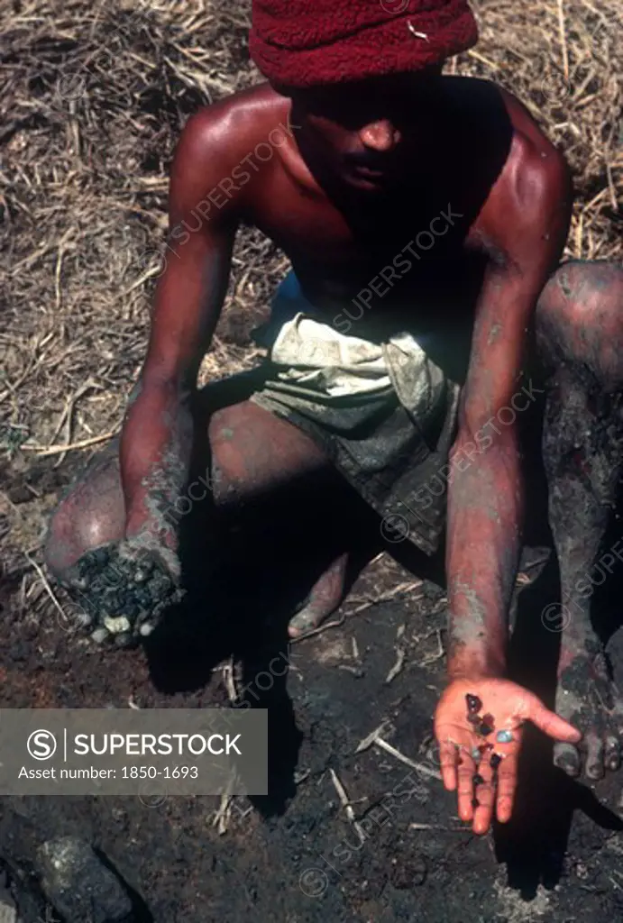 Sri Lanka, Ratnapura, Gem Miner Displaying Gems In One Hand And Unpanned Mud In Other.