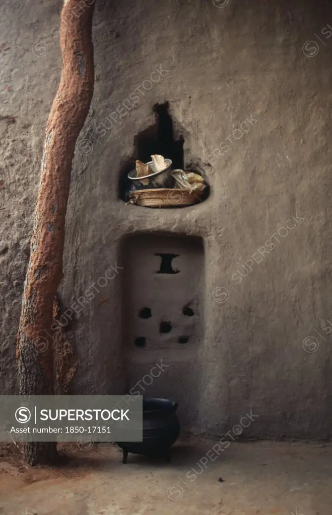 Mali, Housing, Detail Of Mud Brick House Near Kayes With Bowl And Basket In Niche In Wall And Cooking Pot On Ground Outside.