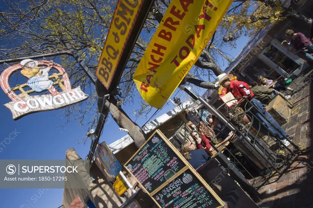 Usa, New Mexico, Santa Fe, The Cowgirl Cafe Outdoor Eating Area With Customers And A Waiter. Sign Showing The Days Meals